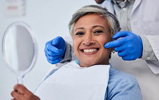 Woman smiling while holding small mirror