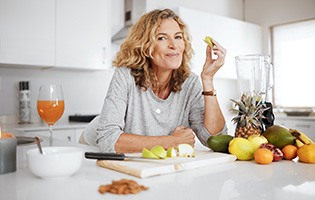 Smiling woman snacking on fruit in kitchen