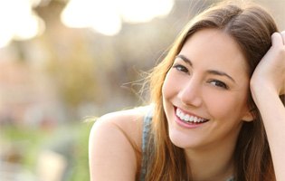 Woman smiling outdoors in late afternoon sun