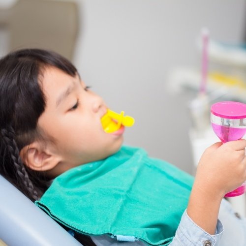 Child receiving fluoride treatment in dental chair