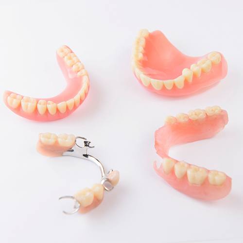 Full and partial dentures arranged in a circle on white surface