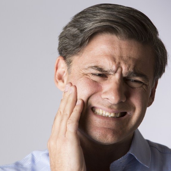 Man holding cheek in pain needing emergency dentist in Fair Oaks