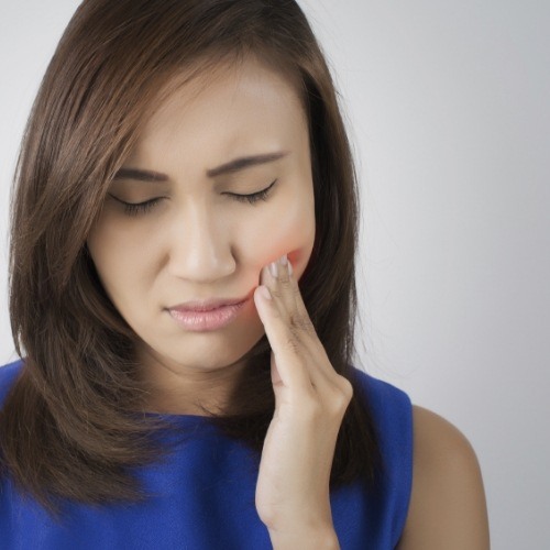Woman holding side of her face in pain