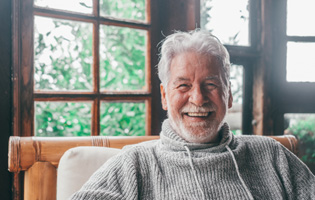 Man smiling while sitting in his rustic cabin in the woods