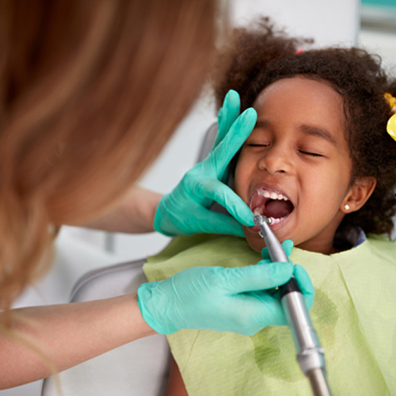 a child having her teeth polished by a dental hygienist