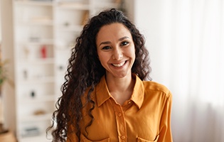 Woman in orange shirt smiling at home