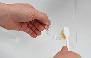 Patient cleaning clear aligner in sink