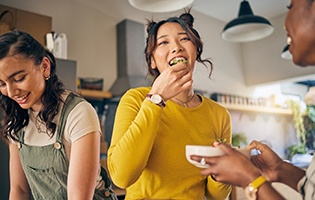 Group of friends smiling while preparing meal in kitchen
