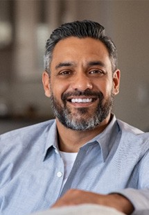 Mature man in blue shirt smiling on couch in living room
