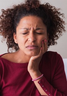 Woman with toothache sitting on couch at home