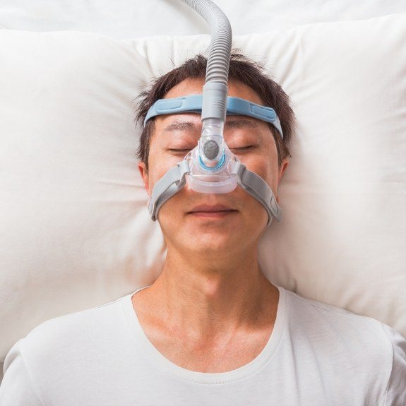 Man sleeping on his back and wearing C P A P mask for sleep apnea treatment
