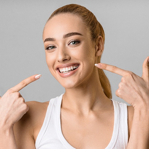 Happy woman pointing at her white, beautiful teeth