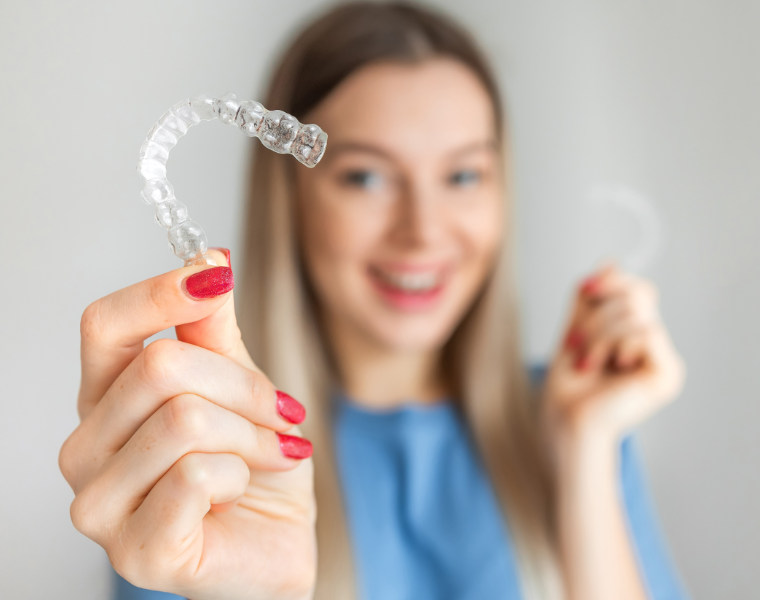 Woman holding up clear aligner